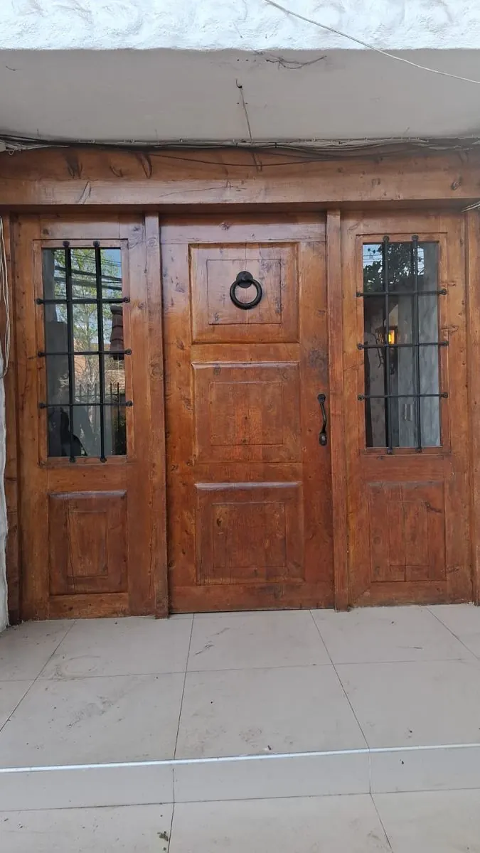 Puerta de entrada de madera maciza, con laterales de vidrio y rejas