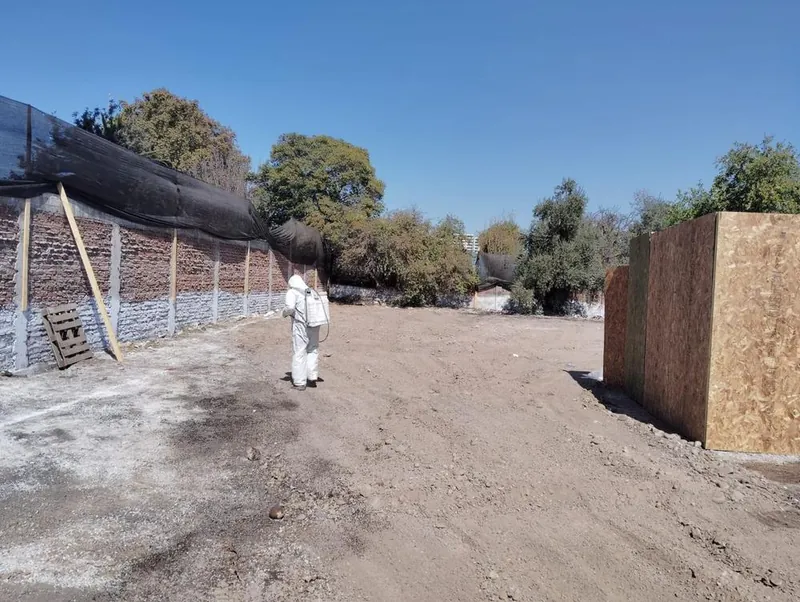 Terreno despejado después del retiro de asbesto, con un operario con traje de protección