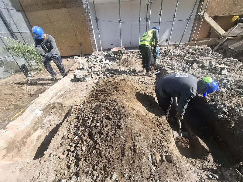 Cuadrilla con casco y chaleco excavando a mano dentro de una obra