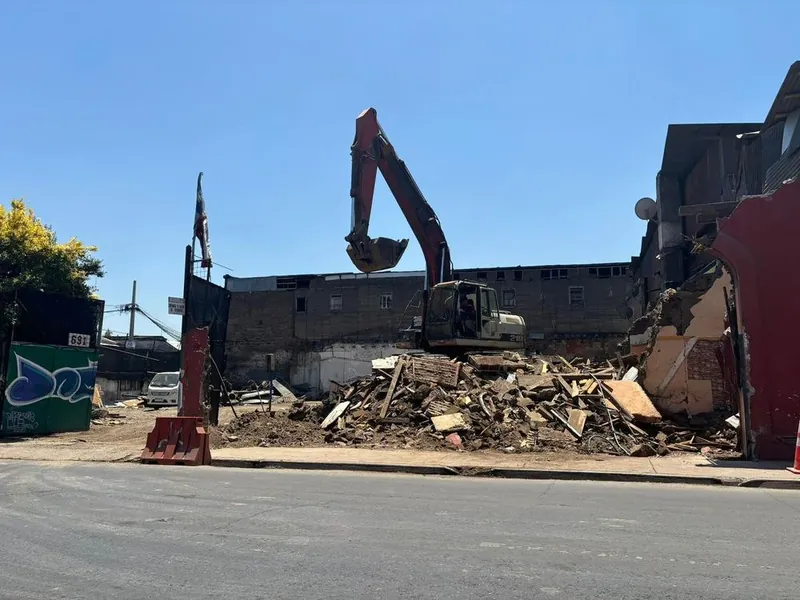 Excavadora demoliendo una construcción con frente a la calle