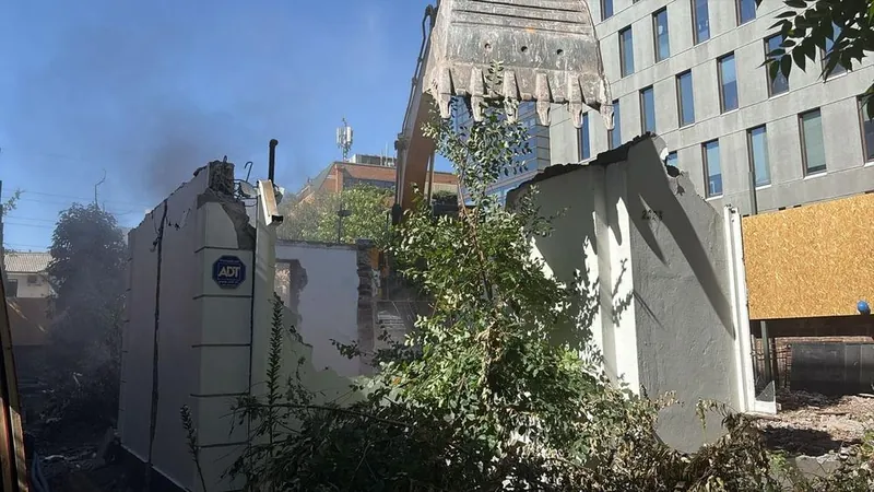 Muros de una vivienda a medio demoler, con el edificio vecino protegido