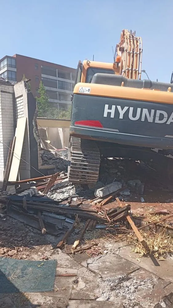 Excavadora Hyundai demoliendo una construcción entre edificios