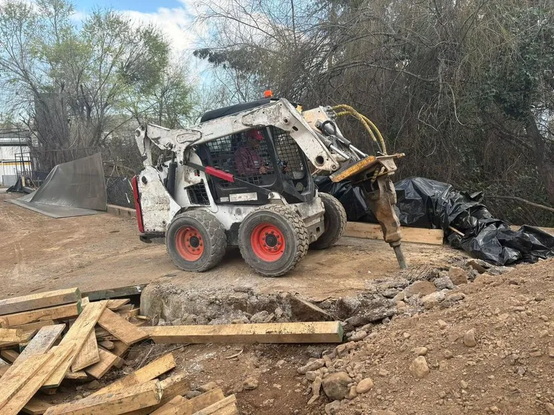 Minicargador con martillo hidráulico rompiendo un radier