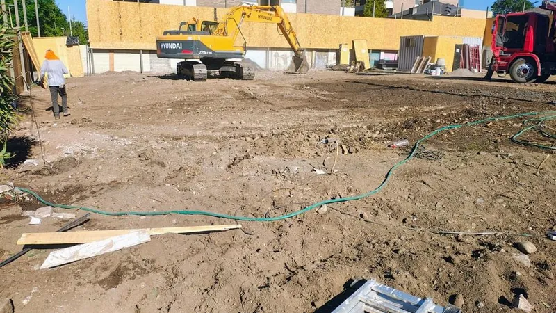 Excavadora y camión cargando escombros en un terreno urbano