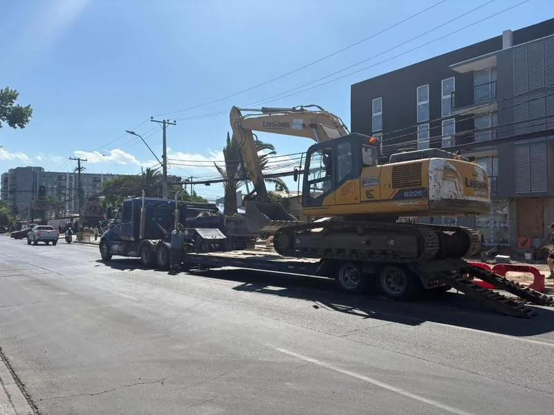 Traslado de una excavadora en camión cama baja por una avenida